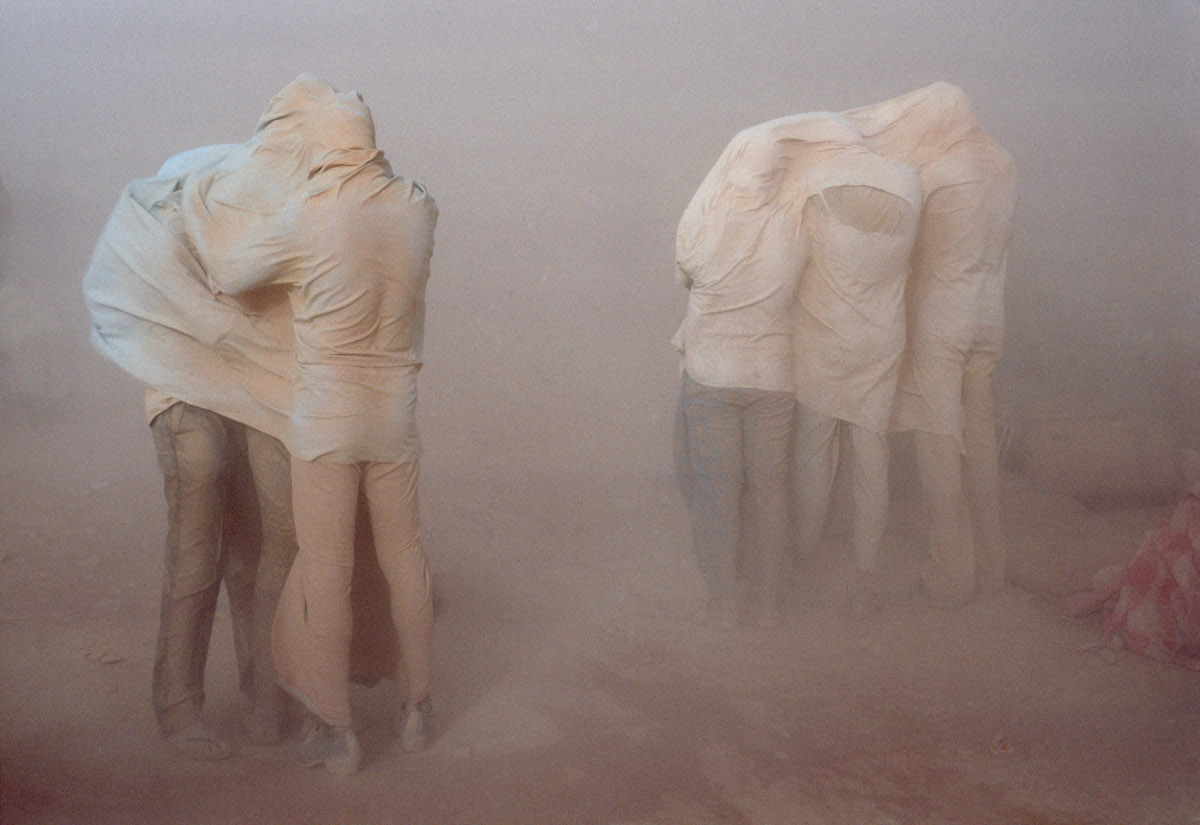 LON42134 Refugees in the desert. People engulfed in a sandstorm waiting for it to subside. Sha-allan ONE camp, Jordan, 1990 © Chris Steele-Perkins / Magnum Photos
